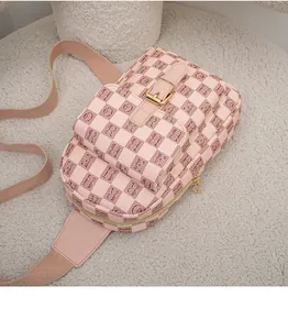 Détail du sac bandoulière rose avec motif à carreaux, lettres et boucle en métal