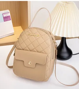 Detail of beige quilted mini backpack featuring a gold metal logo and magnetic flap