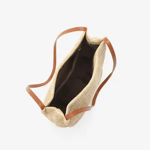 Woven straw tote bucket bag with brown leather straps and interior zip pocket