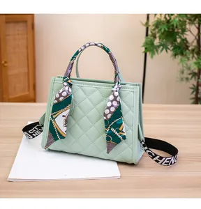 Detail einer hellgrünen Stepphandtasche mit Seidenschal-Dekor und Stoffschultergurt