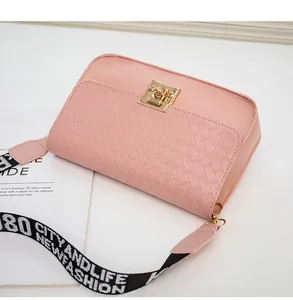 Detail view of pink woven crossbody bag with golden buckle and jacquard strap