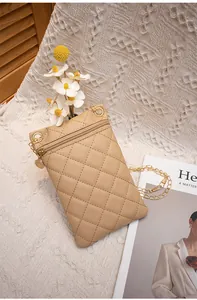 Detail einer khakifarbenen Stepptasche mit goldener Kette auf weißem Strickhintergrund