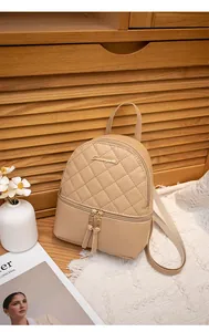 Detailed view of beige PU leather mini backpack featuring diamond quilted stitching and a gold logo