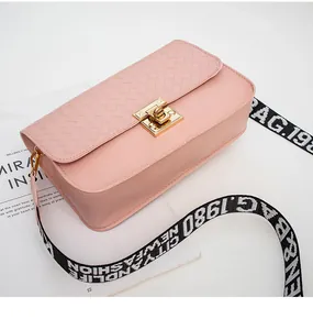 Detail of pink crossbody bag featuring woven texture and gold metal twist lock