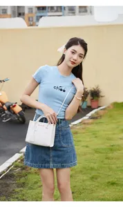 Donna che indossa una borsa a mano bianca in pelle con una sottile tracolla all'aperto