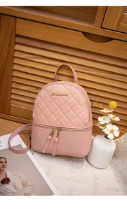 Close-up of pink quilted leather mini backpack with gold logo and tassel details