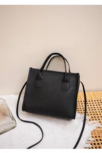 Dettaglio borsa nera in pelle a grana di litchi con manici su base decorativa intrecciata