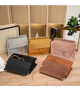 Detail of five crossbody flap bags in various colors with gold rings on a wooden desk