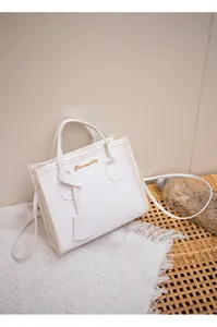 Dettaglio borsa a mano bianca texture litchi con logo dorato su pizzo elegante