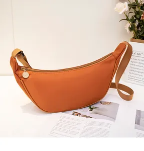 Detail of terracotta crescent bag with gold zipper and durable wide fabric strap