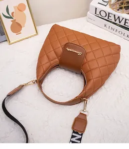 Detail of brown quilted hobo handbag featuring gold metal logo and woven strap