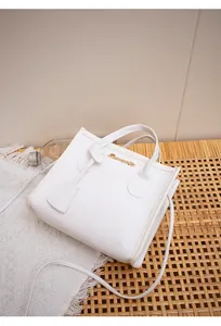 Dettaglio della mini borsa bianca testurizzata con logo dorato su sfondo intrecciato