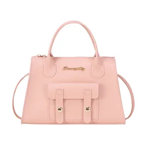 Sac à main trapèze rose en similicuir avec logo doré et bandoulière sur fond blanc