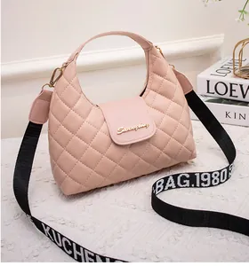 Detailed view of pink quilted handbag with gold hardware and woven logo shoulder strap