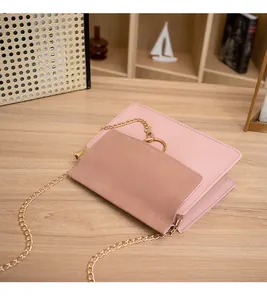 Detailed view of pink and brown crossbody bag with gold chain and circular metal hardware