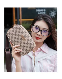 Detail of monogram pattern and brand logo on beige crossbody bag with woven strap