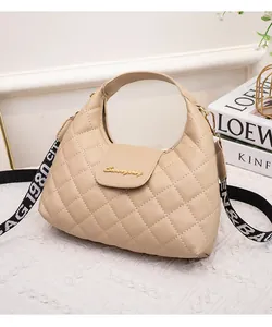 Detail of beige quilted handbag with gold S-logo and stylish lettered fabric strap