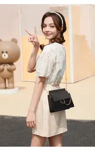 Outdoor shot of a black small square crossbody bag with iconic gold metal ring detail