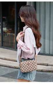 Action shot of the beige plaid crossbody camera bag styled with a casual outfit