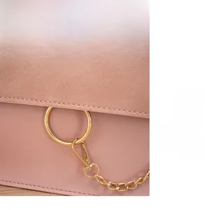 Detail of pink crossbody bag featuring a golden circular ring lock and textured fabric