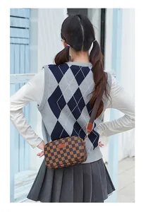 Detail of checkered crossbody camera bag with wide strap and golden metal hardware hooks
