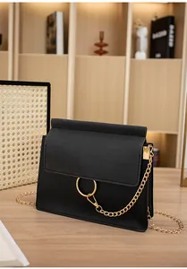 Detail shot of black suede crossbody bag with gold metal ring and elegant chain strap