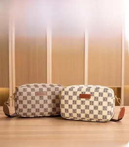 Detail of checkered canvas crossbody camera bags with leather trim and wide straps