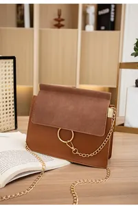 Detail of a brown leather crossbody bag with a gold metal ring and elegant chain strap