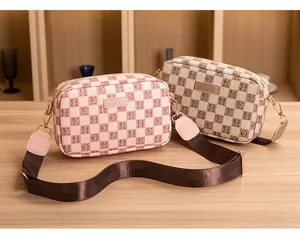 Detail of crossbody camera bags featuring lettered grid pattern and wide nylon straps