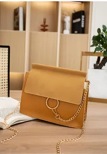 Detail of mustard crossbody bag with matte flap, golden ring buckle, and chain strap