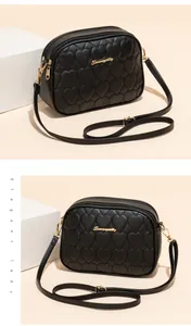 Detalle de bolso acolchado de corazón negro con cremalleras doradas dobles