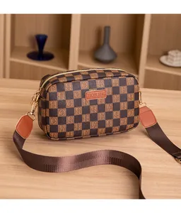 Detail view of checkerboard pattern camera bag with gold hardware and logo patch
