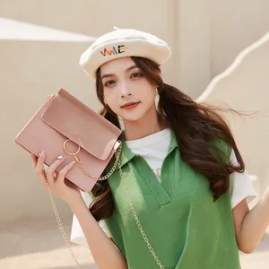 Pink crossbody bag with gold ring buckle and chain strap on a model in sunlight