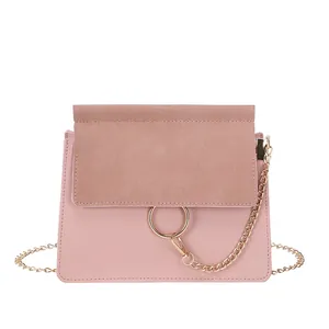 Pink crossbody bag with gold metal ring buckle and chain strap on white background