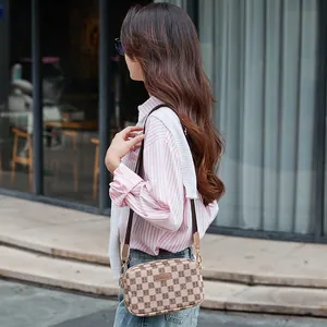 Beige rectangular crossbody bag with lettered grid pattern and wide brown strap
