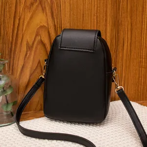 Vertical black crossbody phone bag with flat grain texture and cat pendant accessory