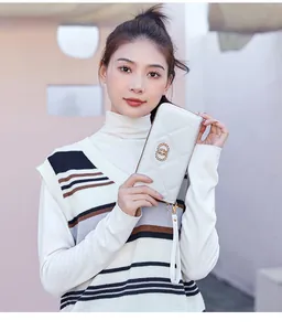 Close-up of cream long wallet with quilted diamond stitching and gold metal ring decor
