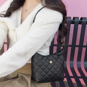 Borsa a tracolla trapuntata nera con fiore dorato indossata da una modella in stile casual