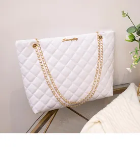 Détail du sac cabas matelassé blanc avec bandoulières dorées et logo métallique