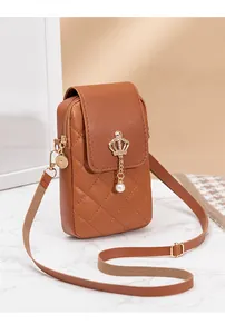 Detail of a brown quilted cross-body phone bag with golden crown charm and pearl pendant