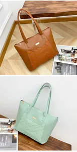 Detail view of large quilted tote bags in brown and mint green with metal pendant
