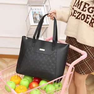 Black quilted faux leather tote bag with gold metal plate detail in a shopping cart