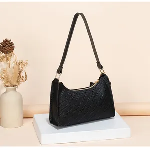 Detail of black woven texture underarm bag with gold hardware on a display stand