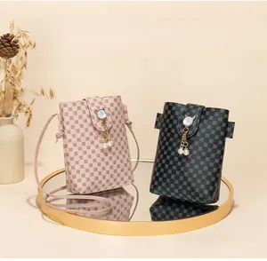 Detailed close-up of patterned crossbody phone bags with pearl tassels on a mirror tray