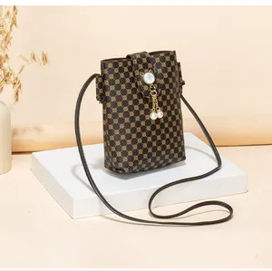 Detail of vintage patterned crossbody phone bag with gold hardware and pearl tassels