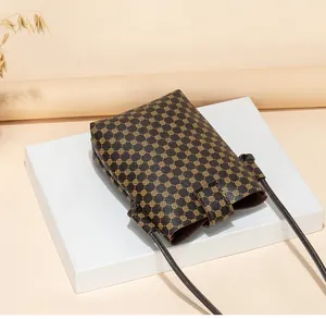 Detailed view of brown crossbody phone bag with golden geometric prints and slim strap