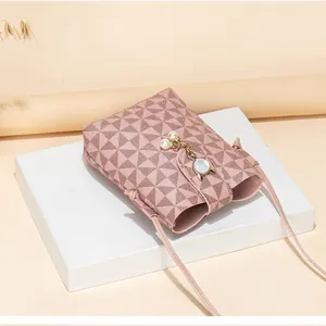 Detail of pink geometric crossbody phone bag with pearl pendant and cat-shaped metal clasp