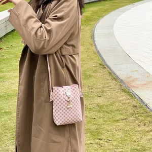 Pink printed crossbody phone bag with pearl tassel pendant worn by model in a park