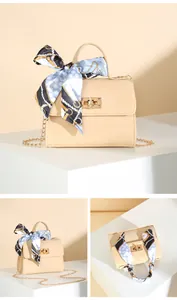 Detail of beige flap square bag featuring a printed silk scarf handle and gold chain strap