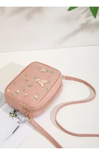 Detail of embroidered pink crossbody bag with 3D butterfly and dual zippers